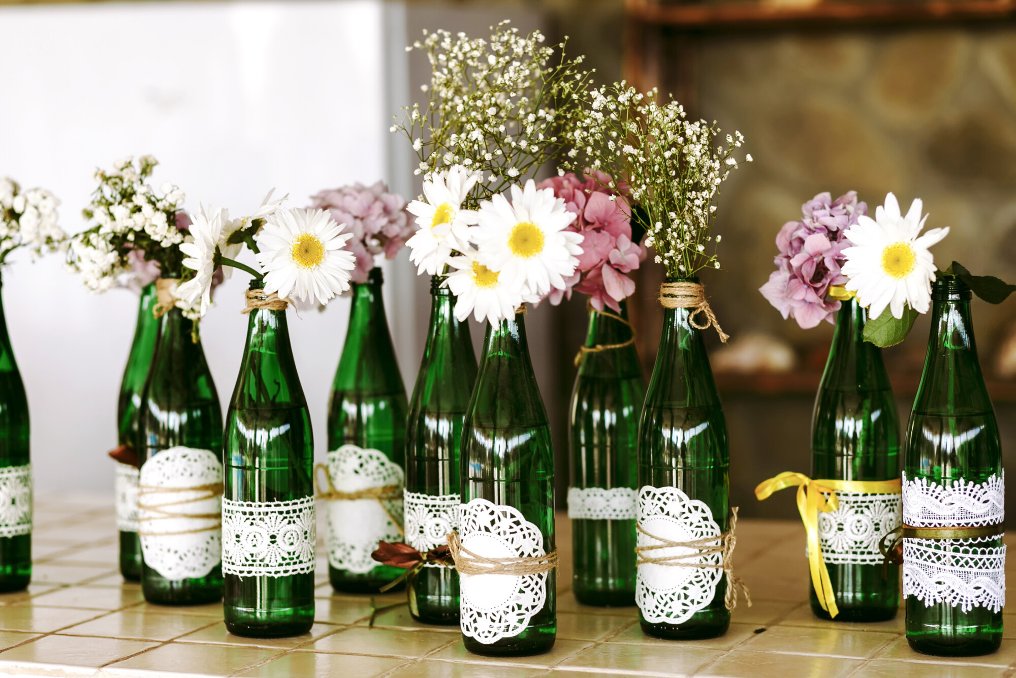 White,Daisies,And,Purple,Hydrangeas,In,Glass,Transparent,Tall,Green Decorative glass bottles with daisies in their necks.