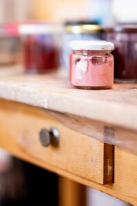 Small jam jar with white lid on a rustic table.