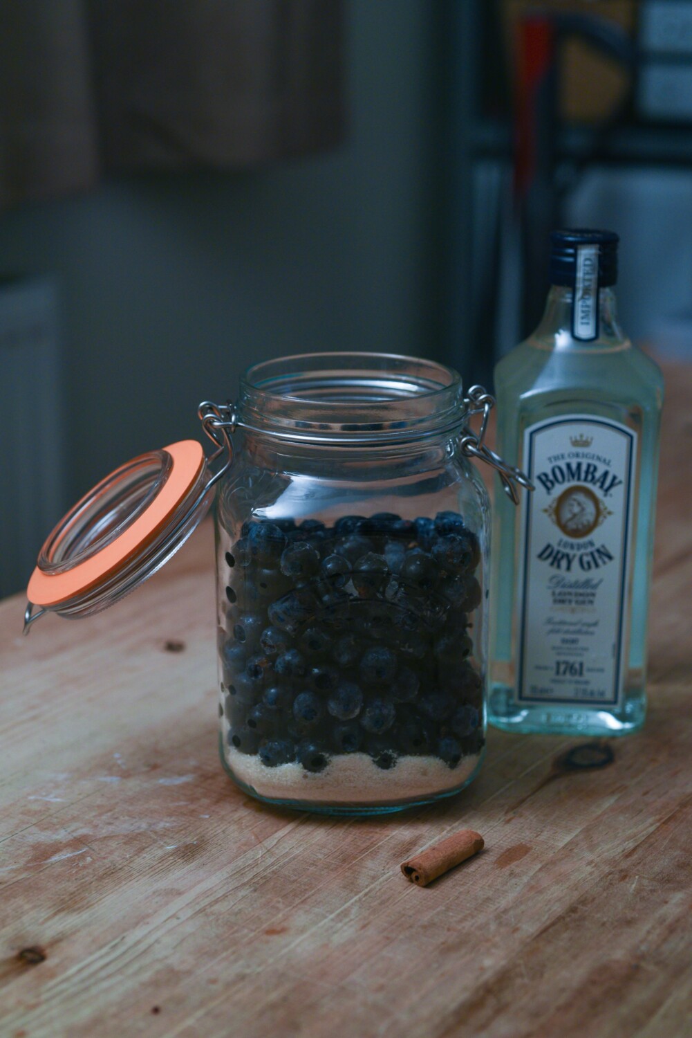 A picture of gooseberries and sloe gin making in a jam jar next to a bottle of gin on a table