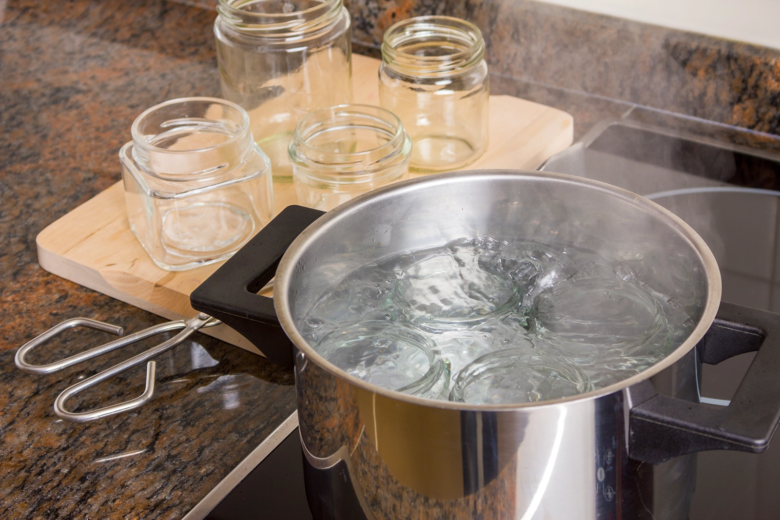 Glass jars being sterilised in boiler water pot Glass jars being steralised in boiling water